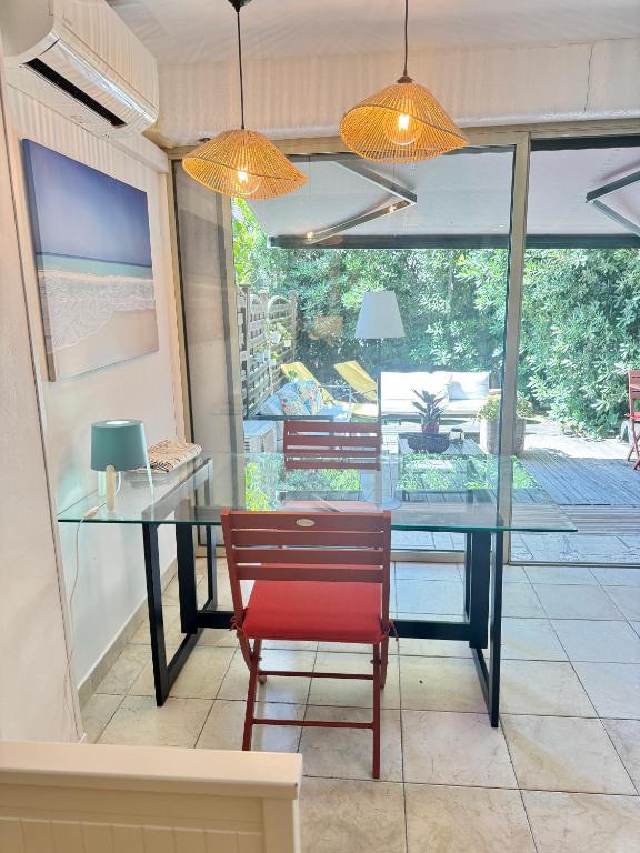 a dining room with a glass table and a red chair at Studio avec jardin sud proche bord de mer in Sainte-Maxime