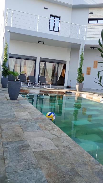 a pool in front of a house with a ball in the water at VILLA ÉKÉ Baguida plage in Baguida