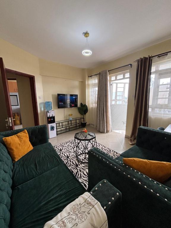 a living room with two couches and a tv at Nesty Homes in Gitura