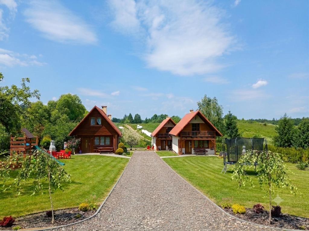 a house in the middle of a field with a driveway at Domki U Tadzia 603-425-844 in Polańczyk