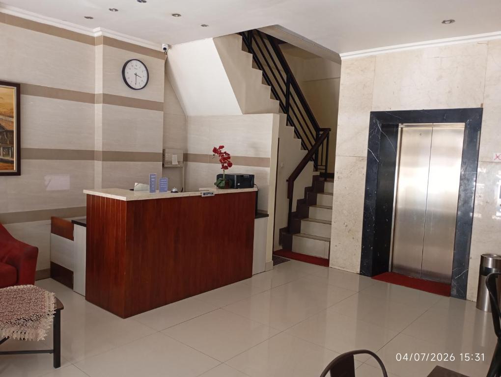 a lobby with a reception desk and a clock on the wall at Legenda Beril Hostel in Makassar