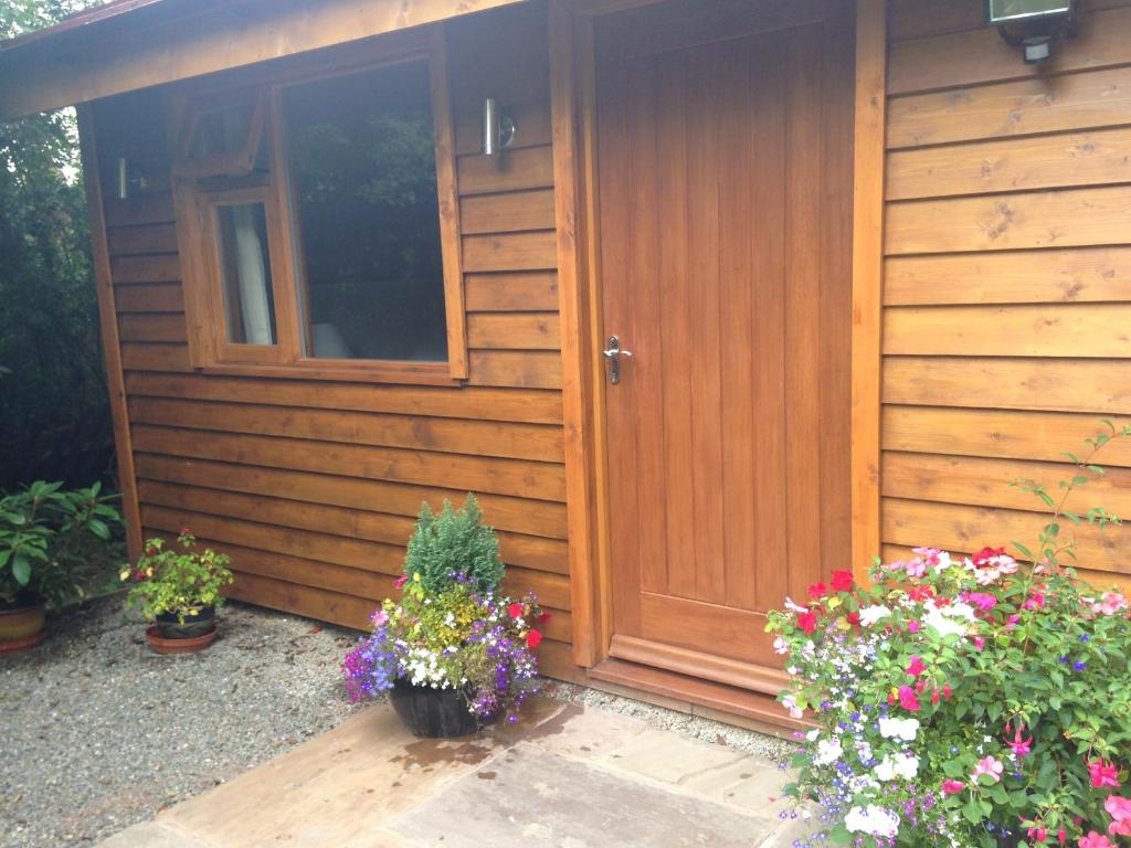 a wooden cabin with flowers in front of it at Manor Garden Lodge in Wirral