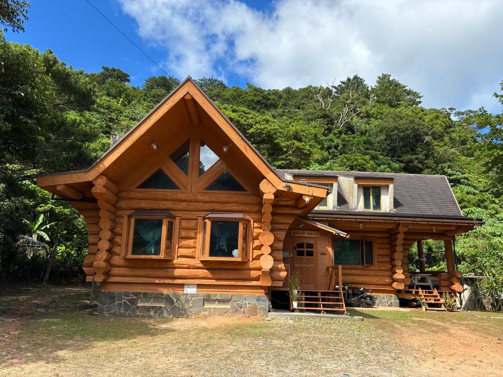 a log cabin with trees in the background at PrivateVillaHutamiLog in Nago