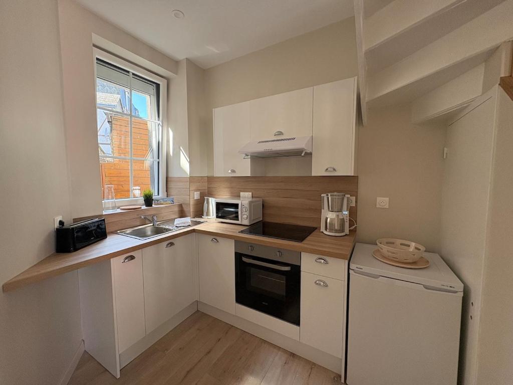 a kitchen with white cabinets and a sink and a microwave at Le Petit Bleu - Charming House in Yport