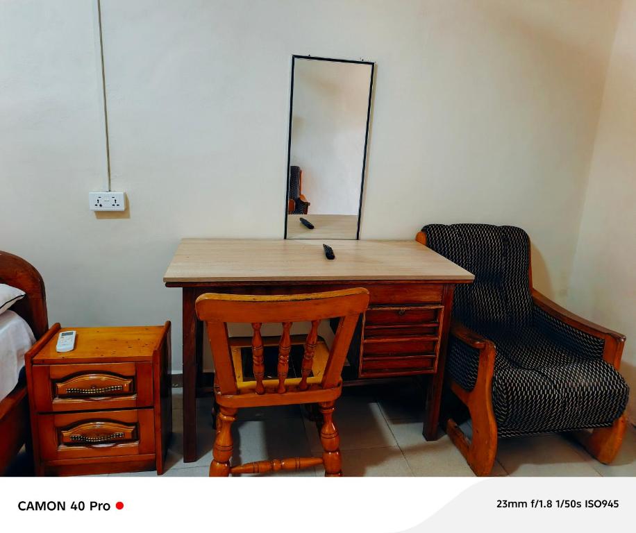 a wooden desk with a mirror and a chair at 0YE' Hotel in Ashalebotwe