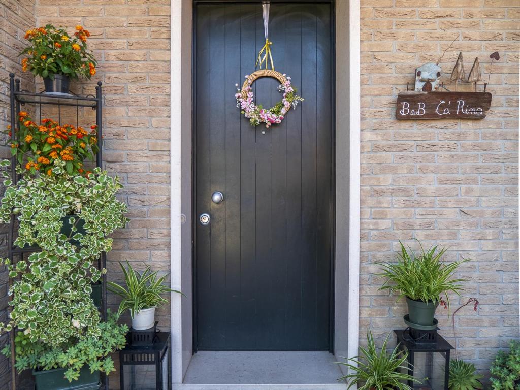 a black door with a wreath on a brick house at B&B Ca' Rina in Preganziol