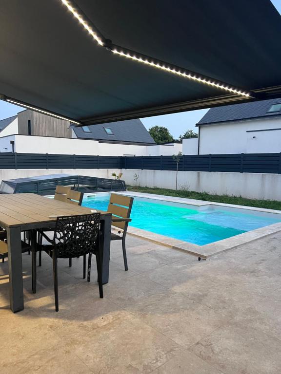 eine Terrasse mit Tisch und Stühlen und ein Swimmingpool in der Unterkunft Ma Bro - ERDIVINES in Erdeven