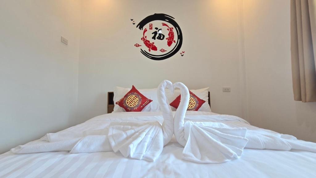 a white bed with two white swans at ฮ่องเต้รักไทยรีสอร์ท in Ban Rak Thai