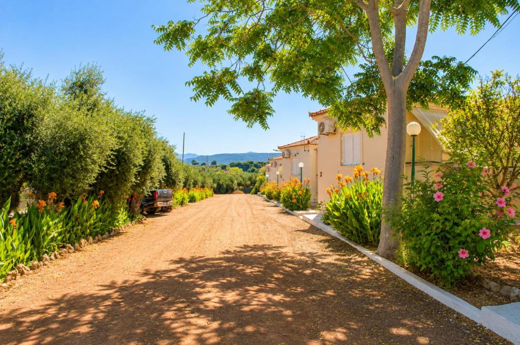 a dirt road with a tree and flowers at Lagouvardos Beach Apartments in Marathopoli