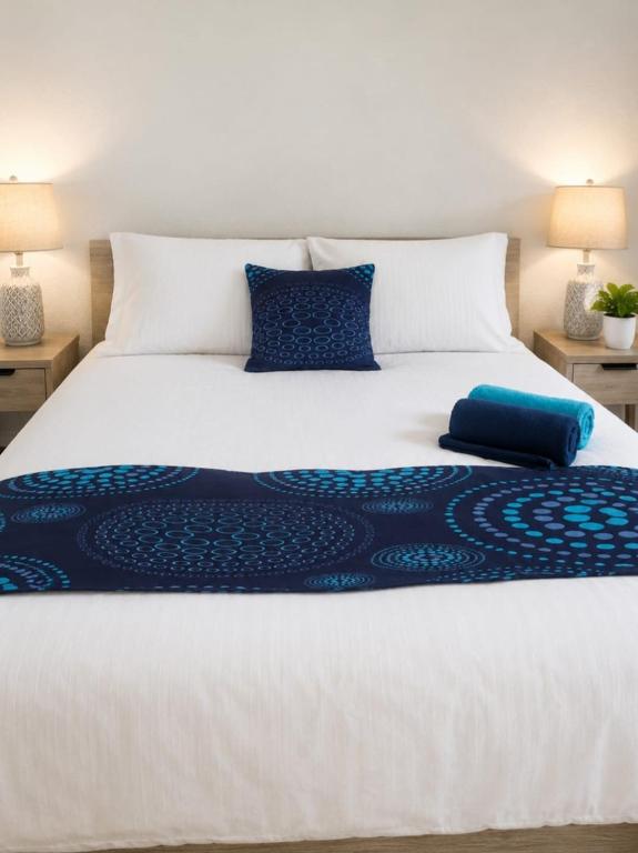 a large white bed with blue pillows on it at Comfortable 2-Bed Flat with Free Parking in Paisley