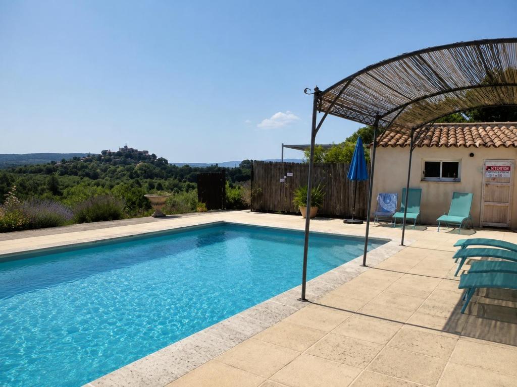 a swimming pool with a pergola next to a house at L'Eden in Ansouis
