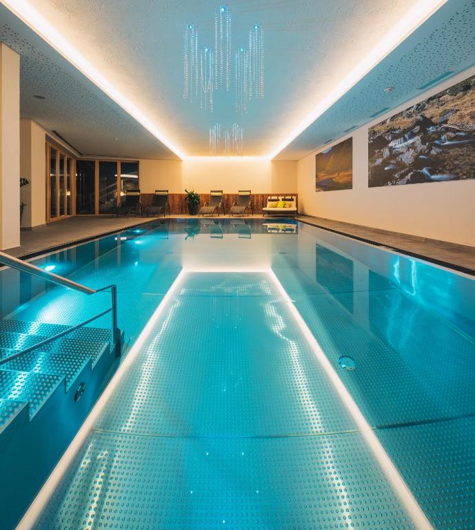 an indoor swimming pool with blue water in a building at Das Landerer in Ladis