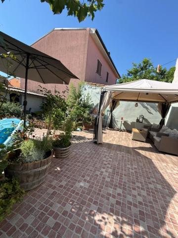 a brick walkway with an umbrella and some plants at Monolocale in un piccolo paradiso in Tramatza