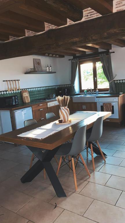 a wooden table in a kitchen with chairs and a table at Gîte des Charbonneaux in Avrée