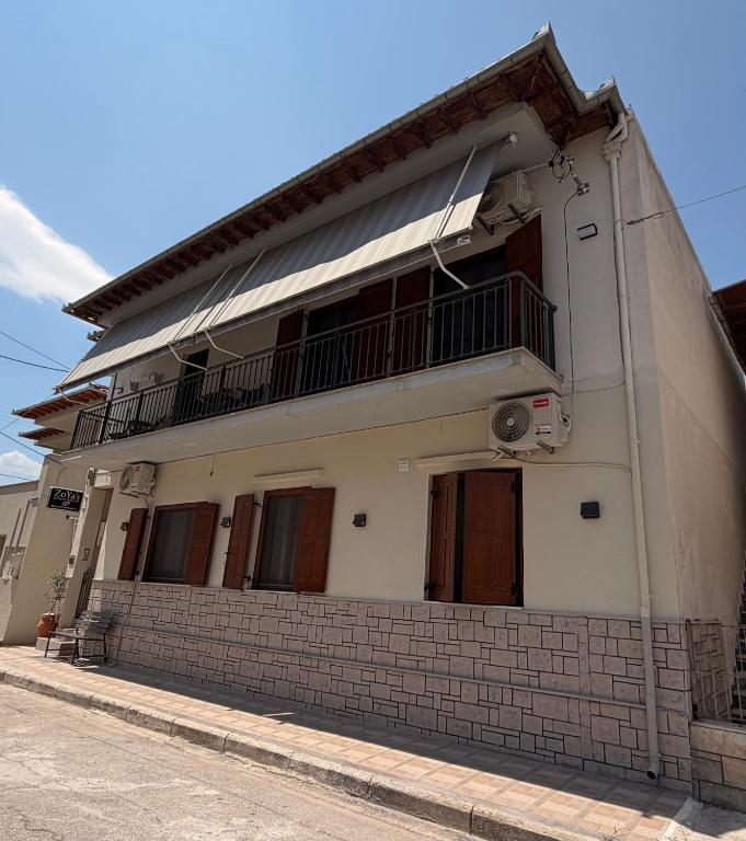 a white building with a balcony on top at ZoYa`s Apartments in Agria