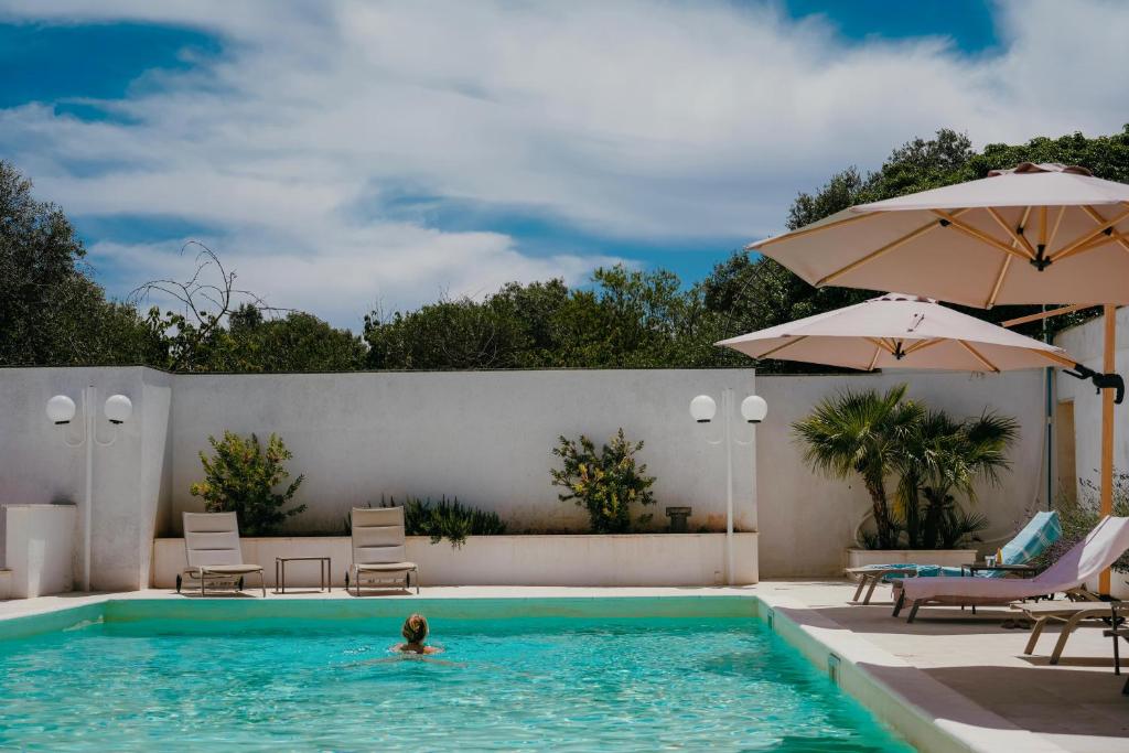 a person swimming in a swimming pool with an umbrella at Castellinaria Country Resort in Castellana Grotte