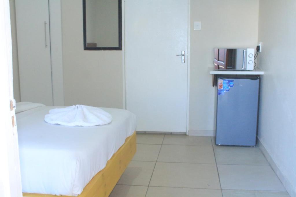 a small room with a bed and a microwave at Prax Guest House Benoni in Benoni