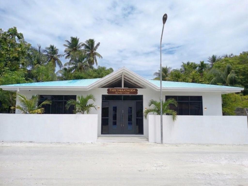 a building on the beach with palm trees at Faresmaathoda Sunset Stay in Faresmathoda