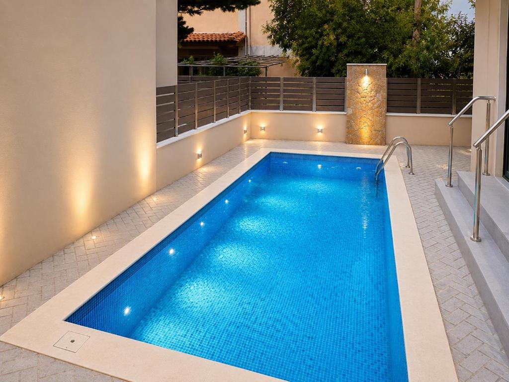 a swimming pool with lights on the side of a house at Agora Luxury Villa II in Loutraki