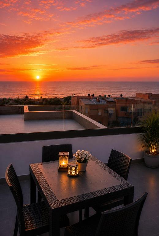a table and chairs on a balcony with a sunset at Cactus Apartment - Walk to Surf Beaches, Rooftop View, Remote Work, Free Parking, AC in Agadir nʼ Aït Sa