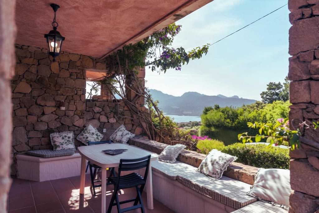 a patio with a table and chairs and a stone wall at Appartamento Monte Ladu in Porto Rotondo
