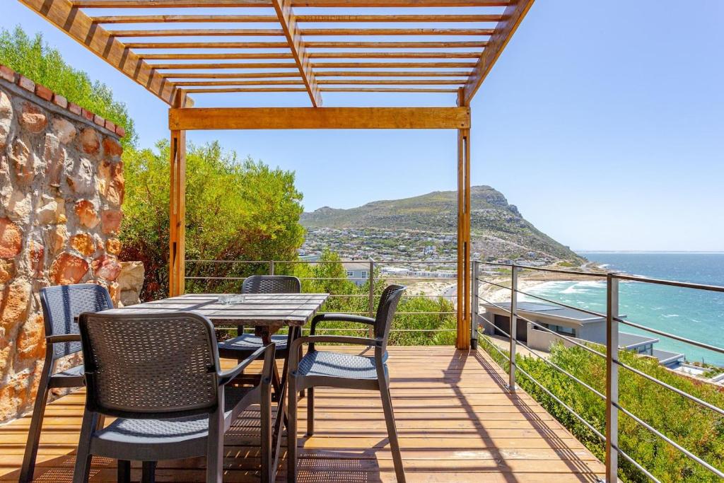 a table and chairs on a deck with a view of the ocean at Beachfront Bliss in Cape Town