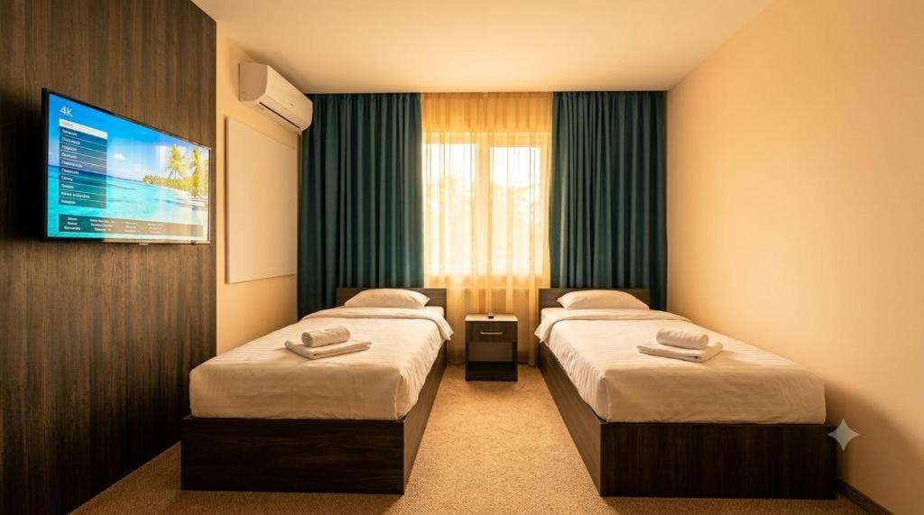 a hotel room with two beds and a tv at Hotel Usmoon in Tashkent