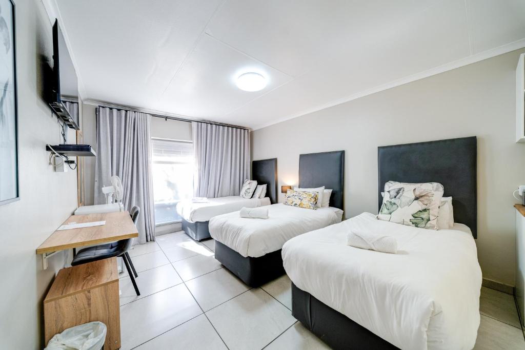 a hotel room with two beds and a desk at 18 Goethe in Secunda