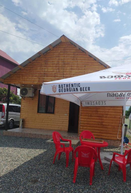 a building with red tables and chairs in front of it at Levani Cottages in Ureki