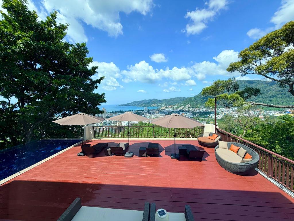 a patio with a couch and chairs and umbrellas at Sunset Bay View Phuket in Patong Beach