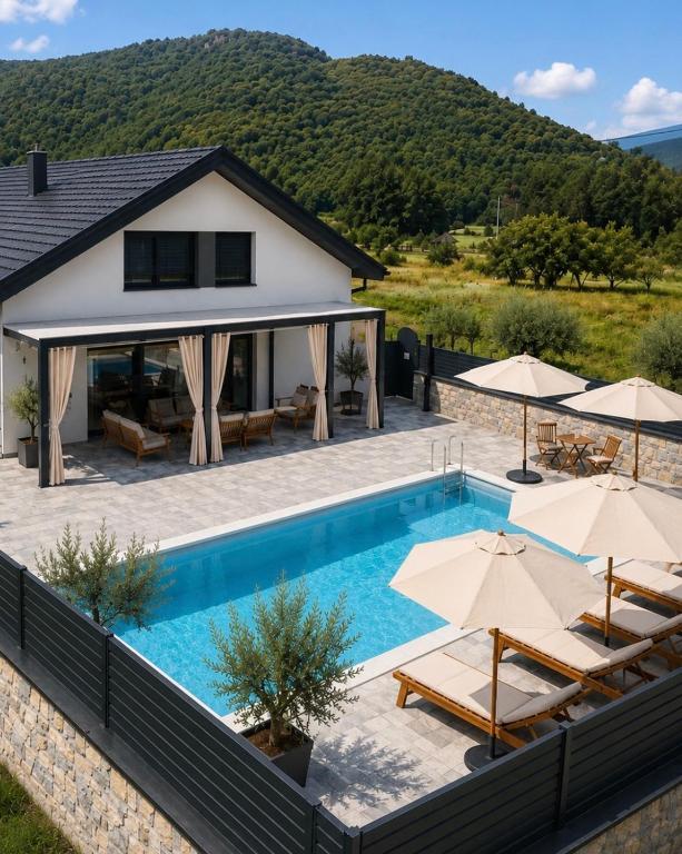a villa with a swimming pool and umbrellas at Villa Aurelia Wellness Bihać in Bihać