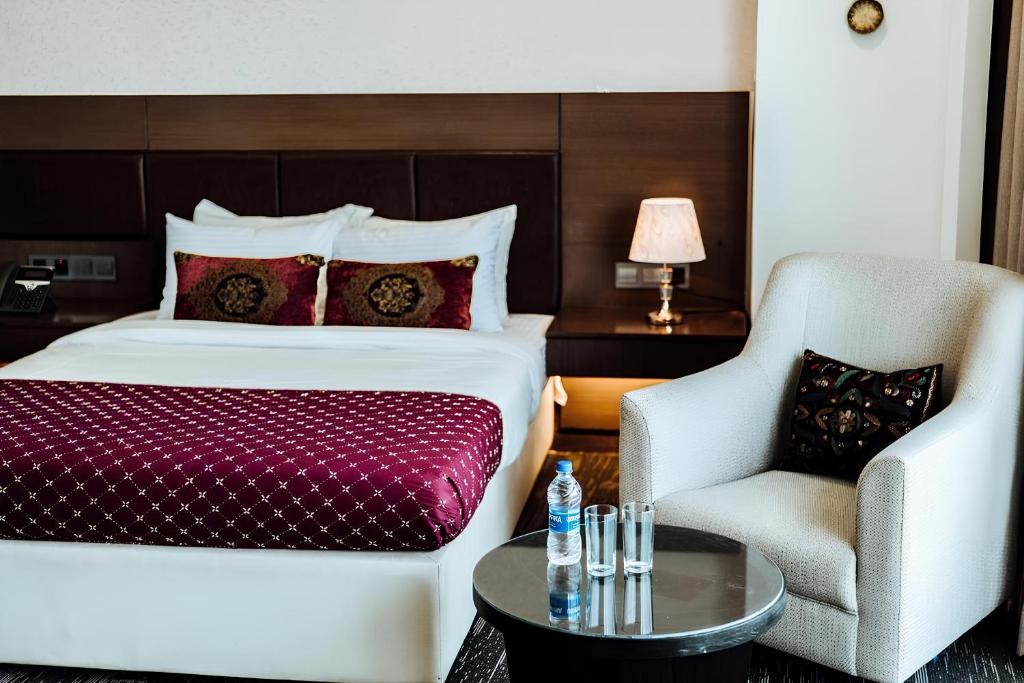 a hotel room with a bed and a chair at Crown Comfortia Hotel Jashore in Jessore