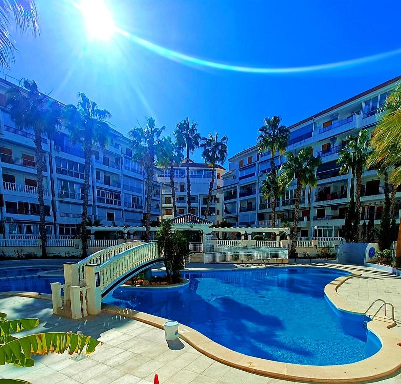 a swimming pool with a bridge in front of a building at Apartament La Mata "FELIZ" in La Mata