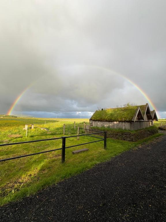 a rainbow over an old barn in a field at Aris place in Hvolsvöllur