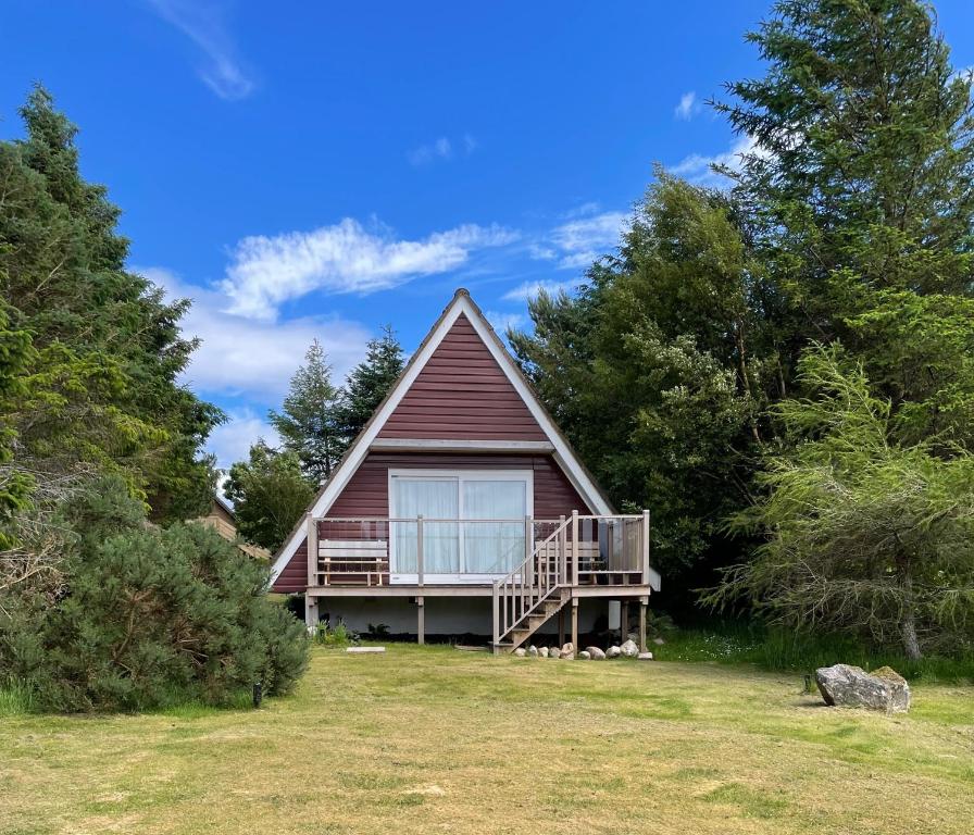 a small house with a porch and a deck at West Haven Lodge in Aultbea