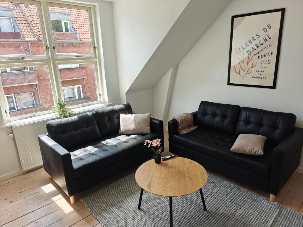 a living room with a black couch and a table at Satellit lejligheder Vejle C in Vejle
