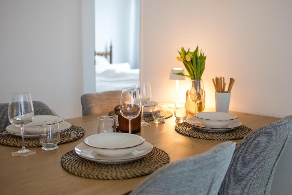 a wooden table with plates and glasses on it at Zentrale City Apartments in Oldenburg
