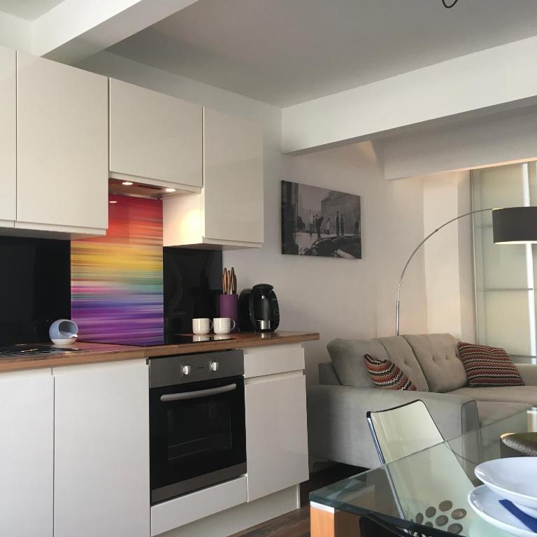 a kitchen and living room with white cabinets and a couch at Over Under Cottage in Holmfirth