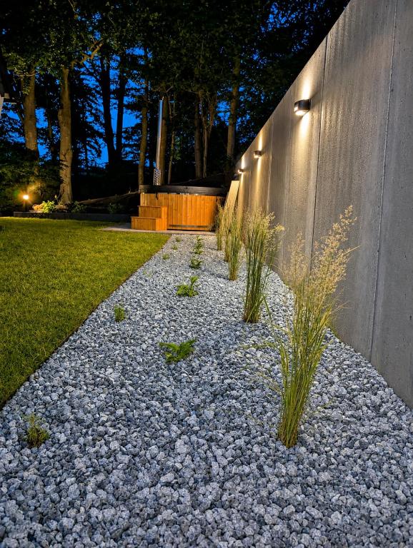 a gravel walkway with plants in front of a wall at Skośne Domki 2 in Chmielno