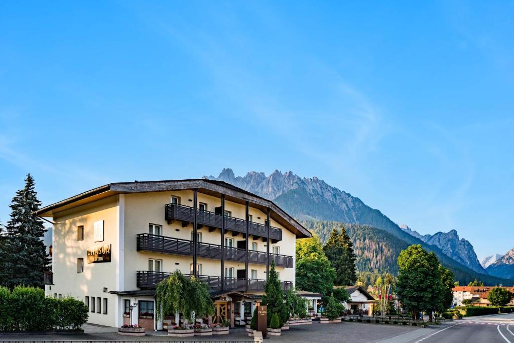 a building with balconies on a street with mountains at Chasca Living in Dobbiaco
