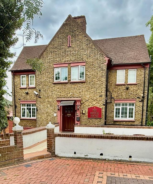 a brick house with a red door at The Bridge House in Hounslow