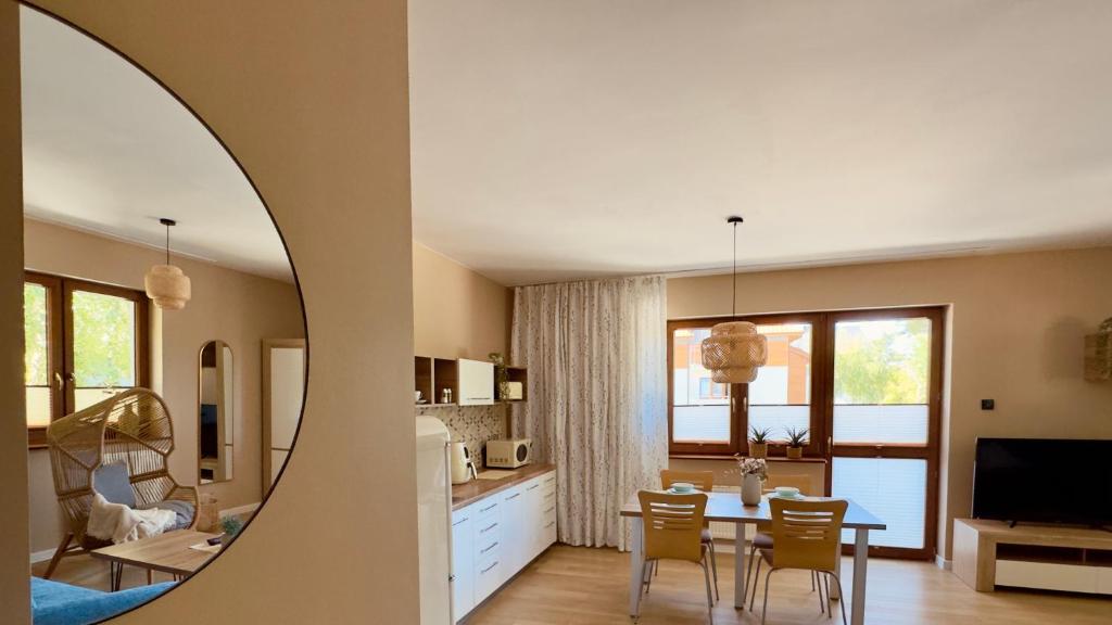 a kitchen and living room with a table and chairs at Rosa Apartamenty in Dąbki