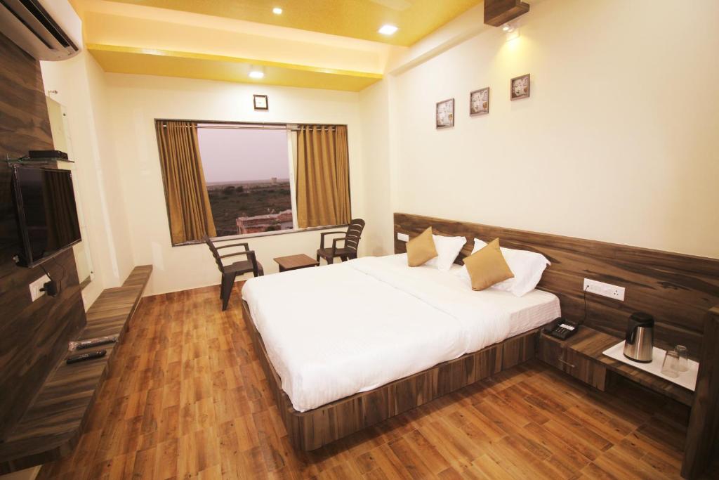 a bedroom with a bed and a table and a window at Hotel Vraj Inn in Dwarka