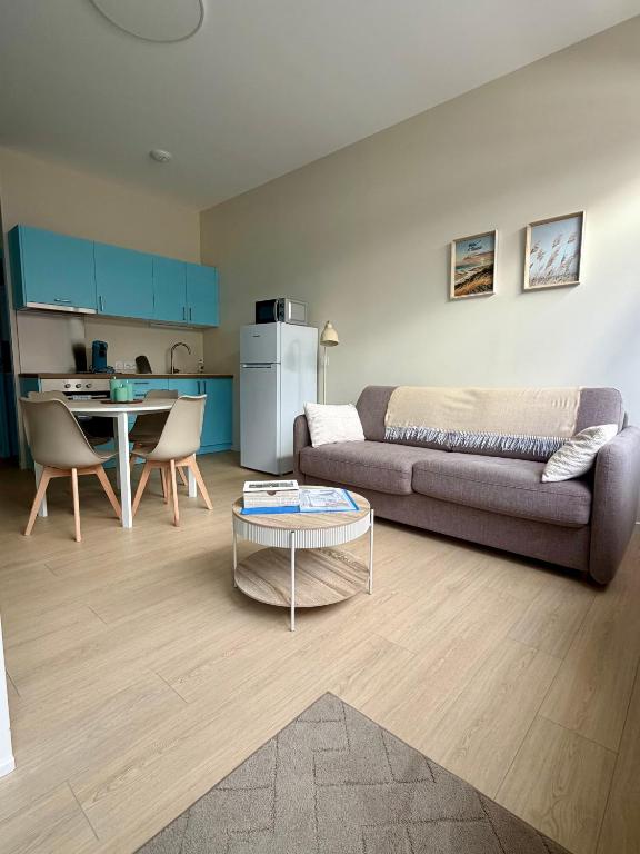 a living room with a couch and a table at Studio des dunes au clocher in Berck-sur-Mer