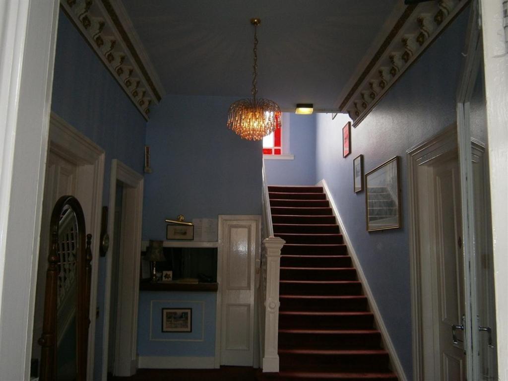 a hallway with blue walls and stairs with a chandelier at Dorstan House in Edinburgh