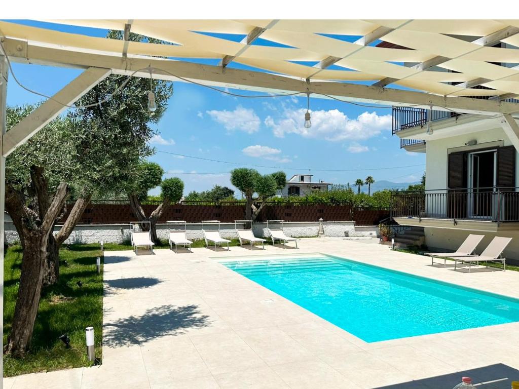 a swimming pool with chairs and an umbrella at Kiro Apartment Experience Pompei in Angri