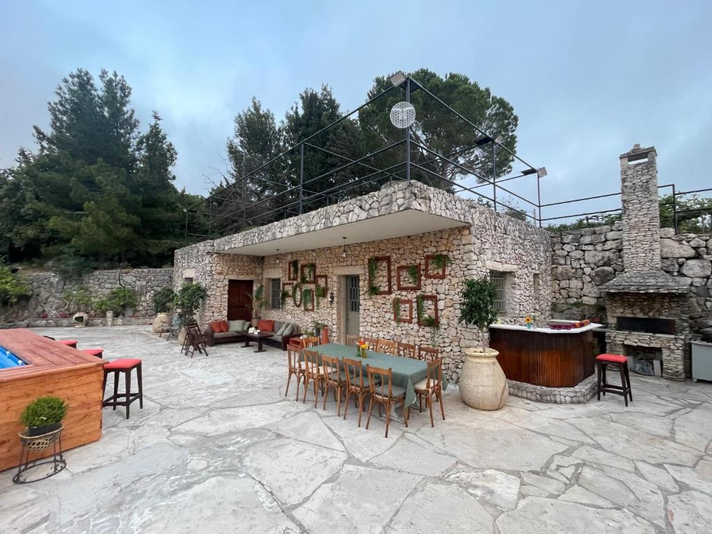 a stone house with a table and chairs and a pool at Maison de Bentaël in Jbeil