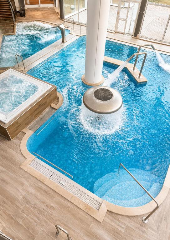 a large swimming pool with a tub in a room at Logis Hôtel & Spa Marina d'Adelphia in Aix-les-Bains
