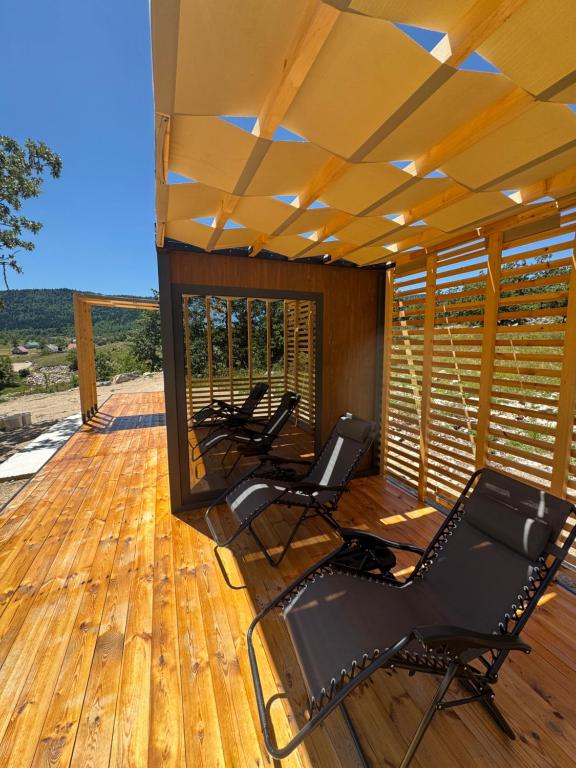 a covered deck with chairs on a wooden deck at Piva Chill in Plužine
