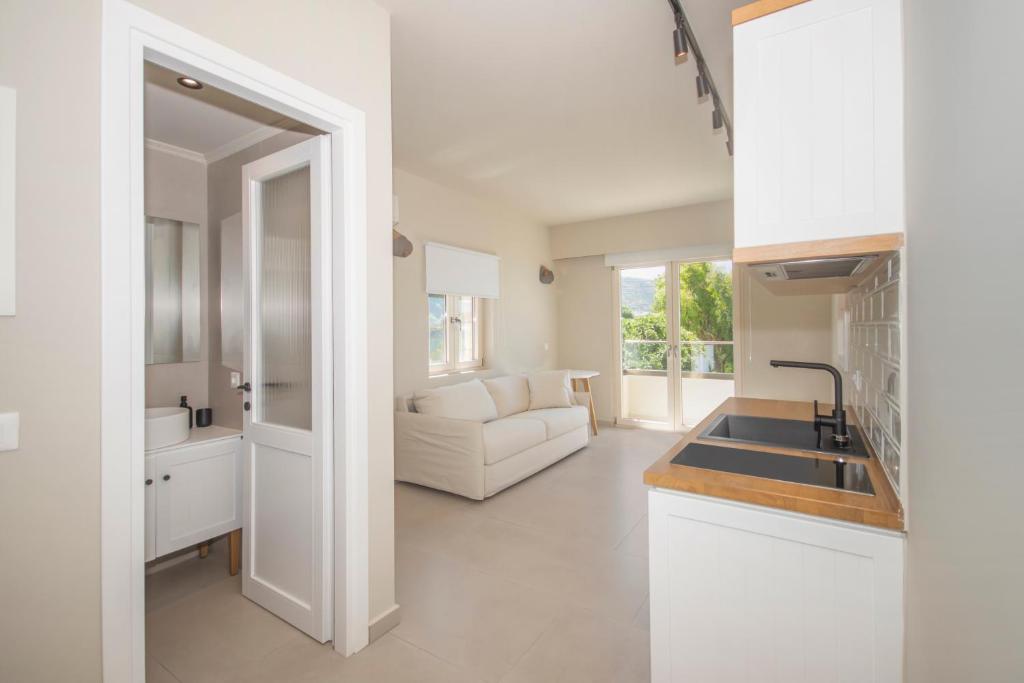 a white kitchen with a sink and a living room at Elia Suites in Falasarna